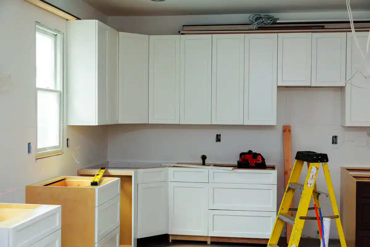 A Suffolk County kitchen under renovation shows white cabinets, tools, and unfinished countertops.