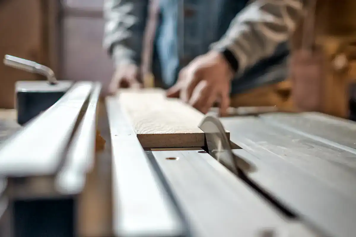 A person in a NY woodworking shop uses a table saw to restore cabinets, hands blurred in motion.